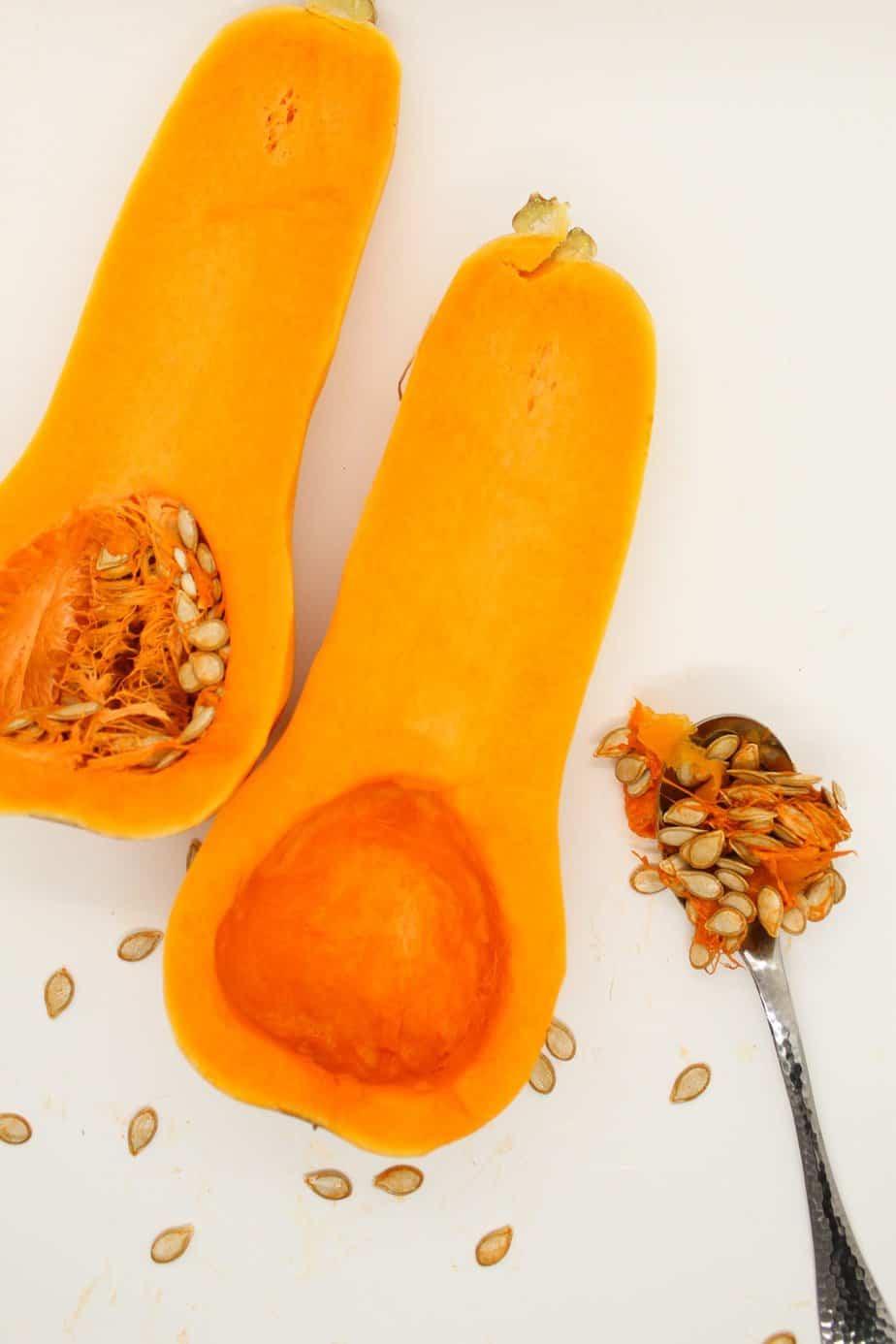 Peeled and halved butternut squash with the seeds removed on a spoon.