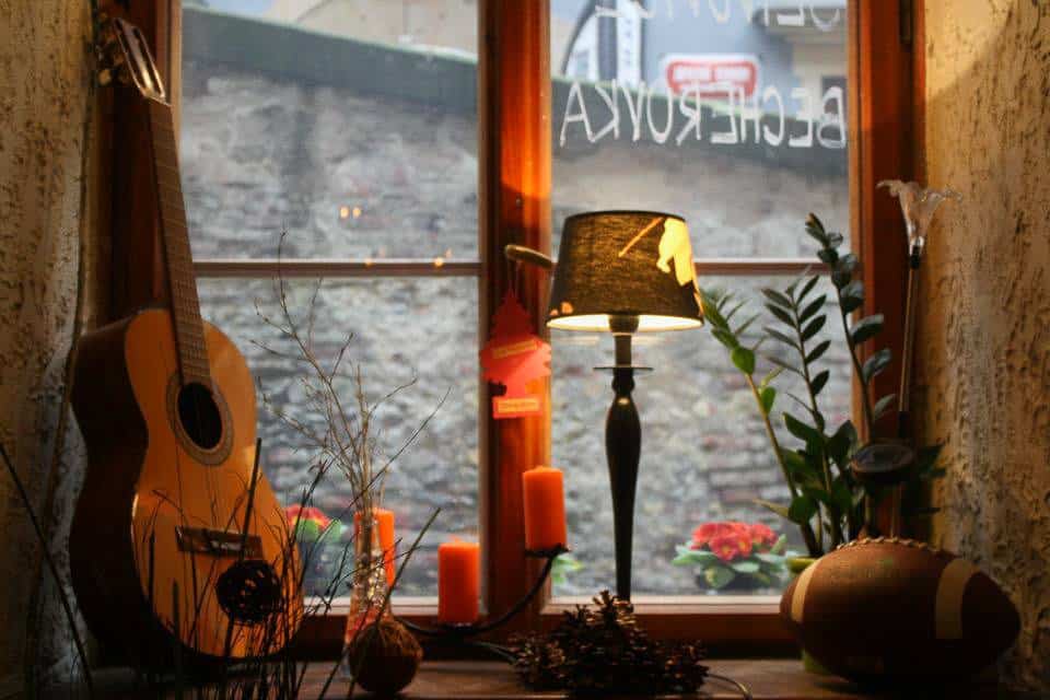 A guitar on a windowsill with a lamp.