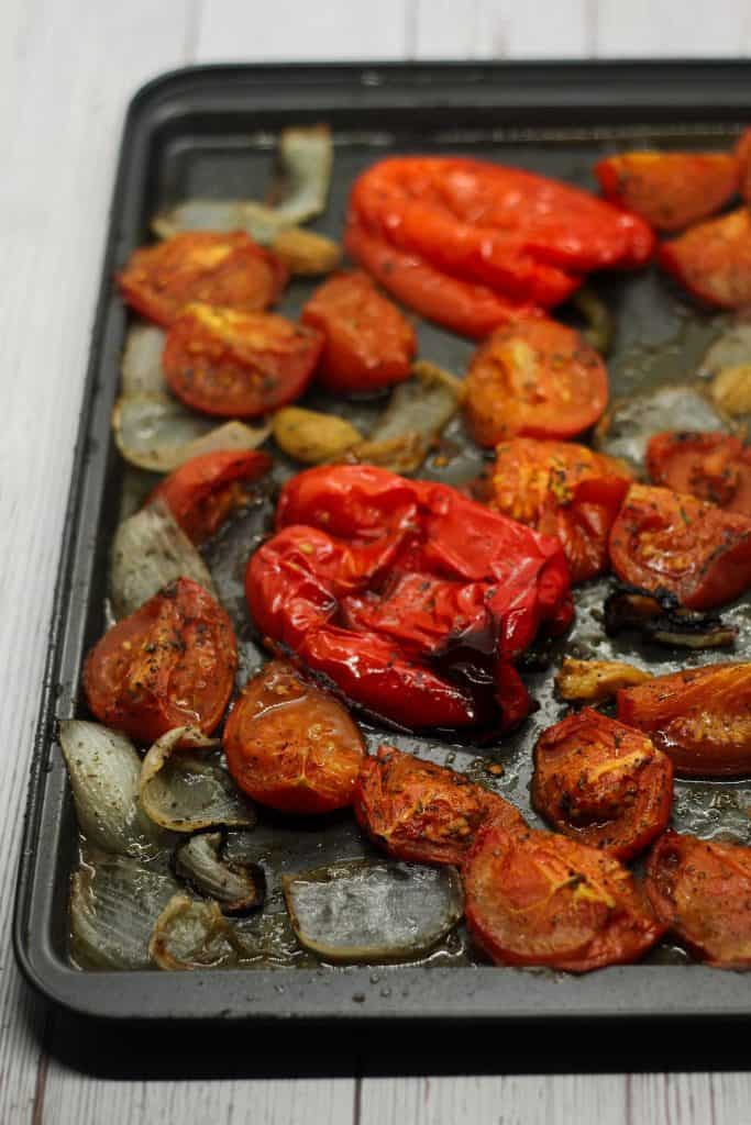 sheet pan with roasted onions tomatoes red bell peppers and garlic