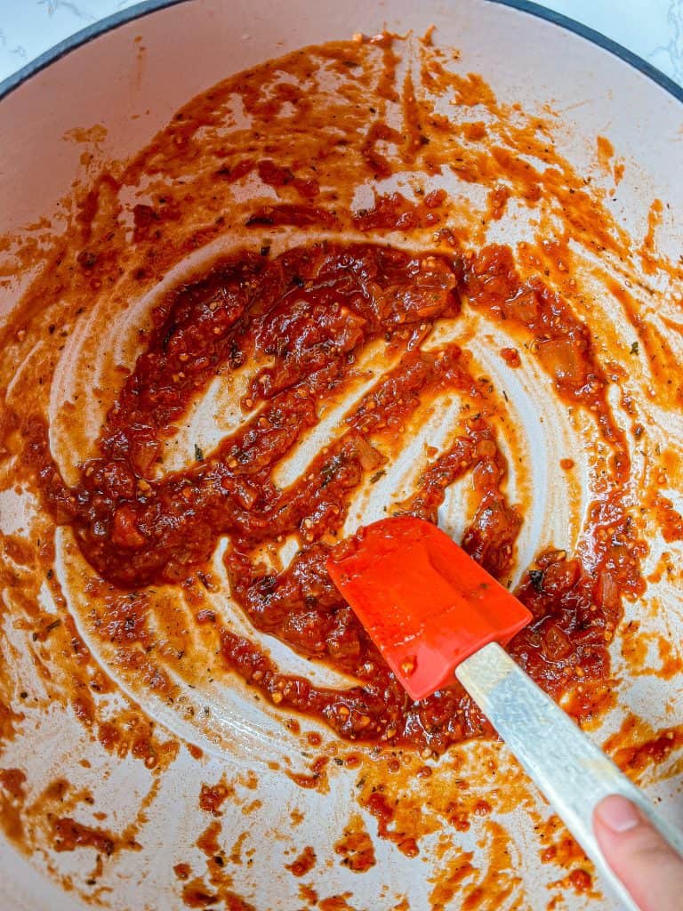 A llittle bit of sauce spread around the bottom and edges of the Dutch oven