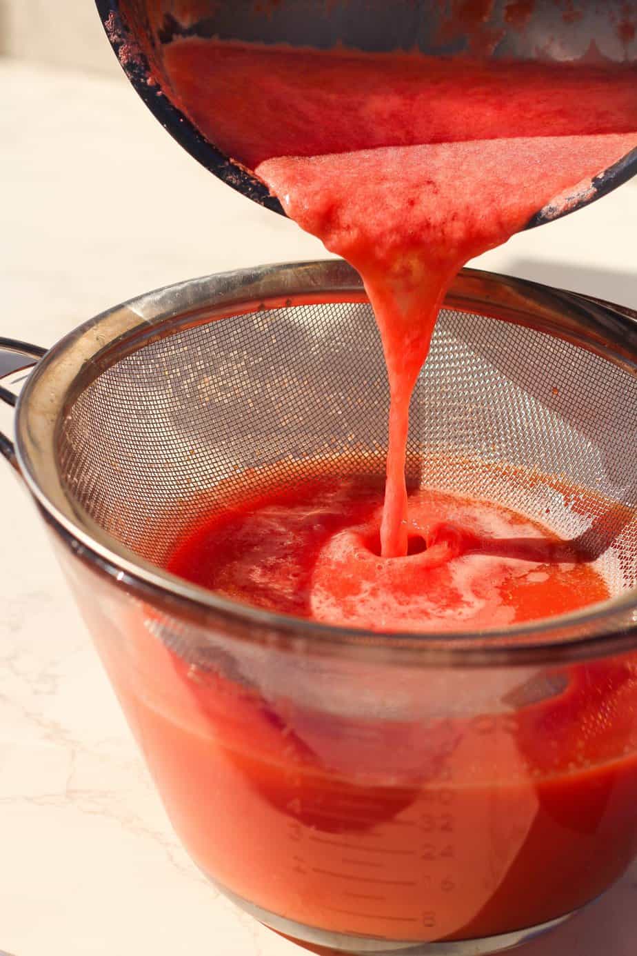 Watermelon Lemon Ginger Juice Wellness Shots Recipe - blended watermelon being strained through a fine mesh strainer