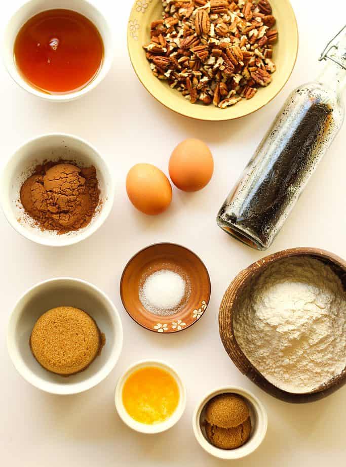 Pecan shortbread bar ingredients in separate bowls on a white surface.
