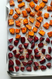 Diced beetroot and pumpkin on a parchment lined silver sheet baking pan.