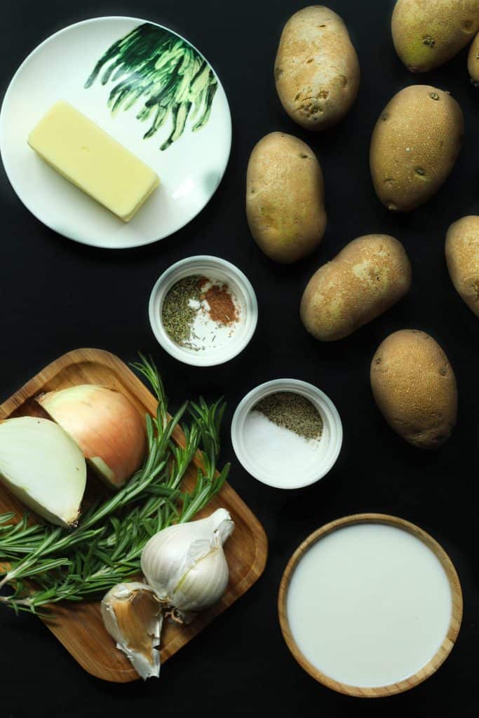 Rosemary garlic mashed potatoes ingredients on a black surface.
