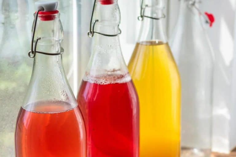 Red and yellow kefir in 3 bottles on a windowsill.
