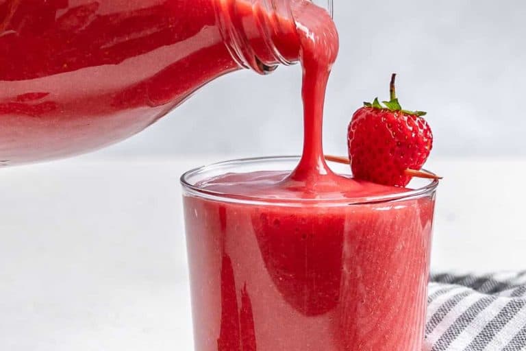 Simple strawberry juice recipe being poured into a glass with a strawberry on a stick.