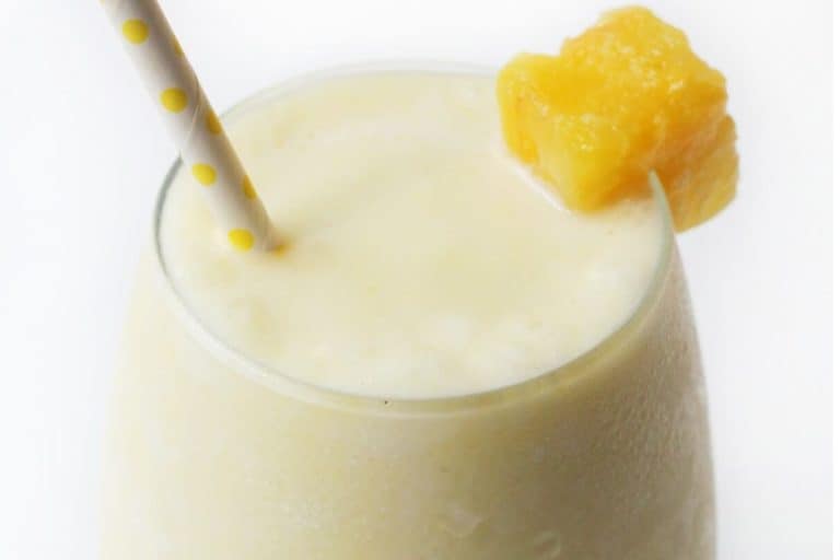 Virgin pina coladas with a mango piece and a white and yellow polka dot straw.