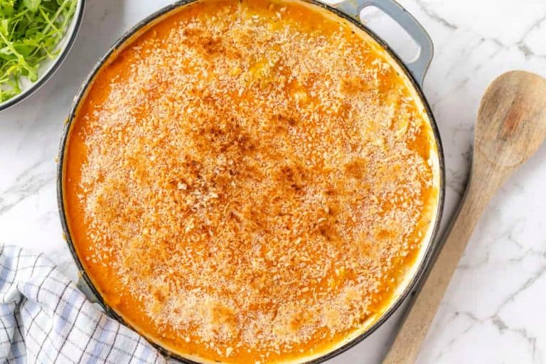 Homemade fall dishes for dinner sweet potato fish pie in a white and gray granite surface and a wooden spoon.