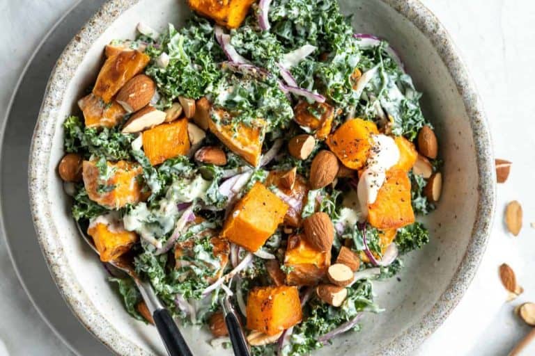 Kale and sweet potato salad with chopped almonds in a gray and white speckled bowl.