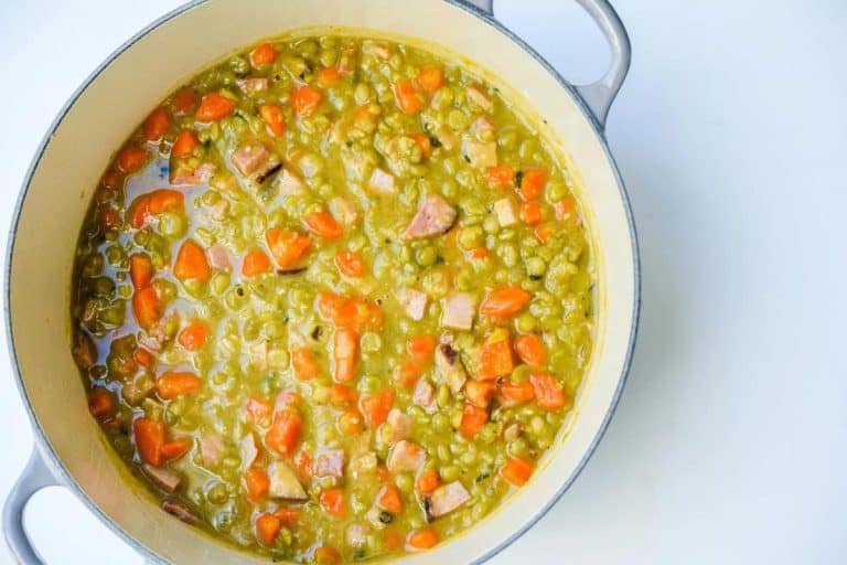 Fall soup ideas: split pea soup with leftover ham and carrots in a round white dutch oven on a white surface.