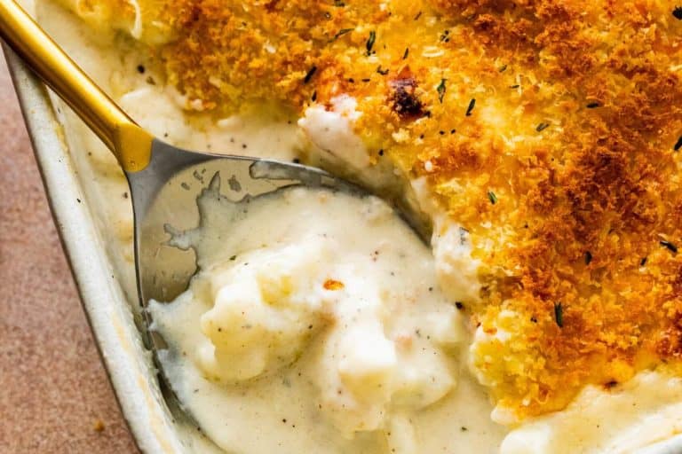 Cheesy cauliflower casserole with a crispy golden-brown topping and a small amount on a golden spoon.