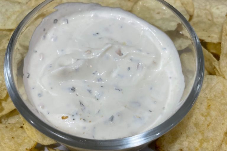 Fall potluck dishes garlic dip recipe in a glass bowl with chips surrounding it.