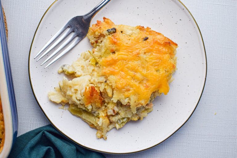 Green chile hashbrown casserole portion on a white speckled plate fall potluck dishes.
