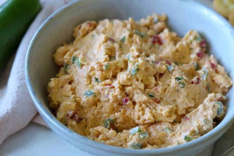 Orange-colored pimento cheese dip with green diced jalapeno and red pimentos in a bowl fall potluck dishes.