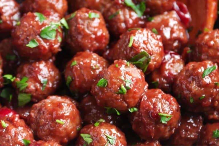 A cluster of cranberry meatballs sprinkled with fresh herbs.