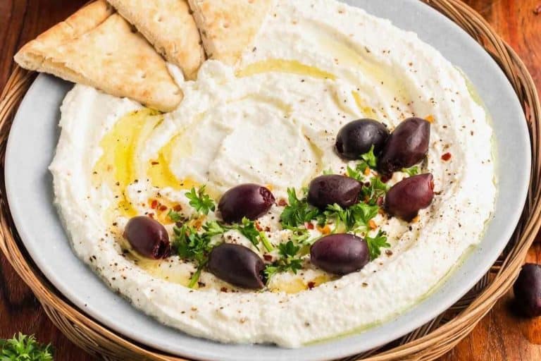 Creamy feta dip topped with whole kalamata olives, fresh herbs, and drizzled with olive oil fall potluck dishes.
