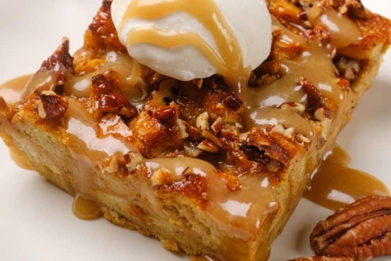 A slice of pumpkin bread pudding drizzled with caramel sauce and topped with ice cream and pecans - fall dessert recipes.