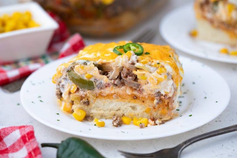 John Wayne casserole topped with sliced jalapenos on a white plate with a red and white checkered napkin.