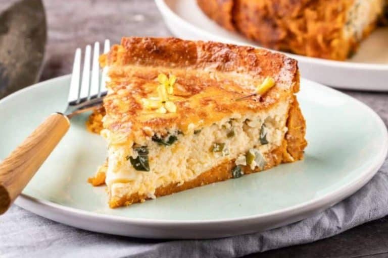Savory sweet potato pie slice on a teal and white plate with a wooden with silver top fork fall potluck dishes.