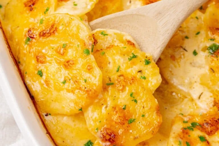 Fall potluck dishes scalloped potatoes topped with minced parsley in a white baking dish.