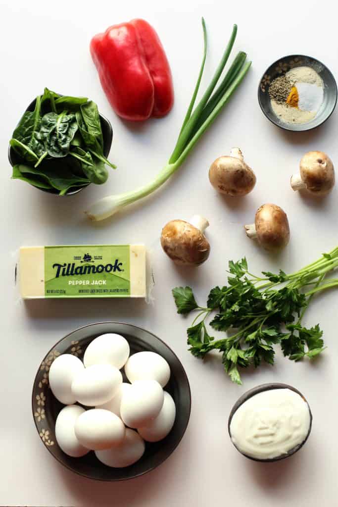 Veggie egg bites recipe ingredients set out in a cluster on a white surface.