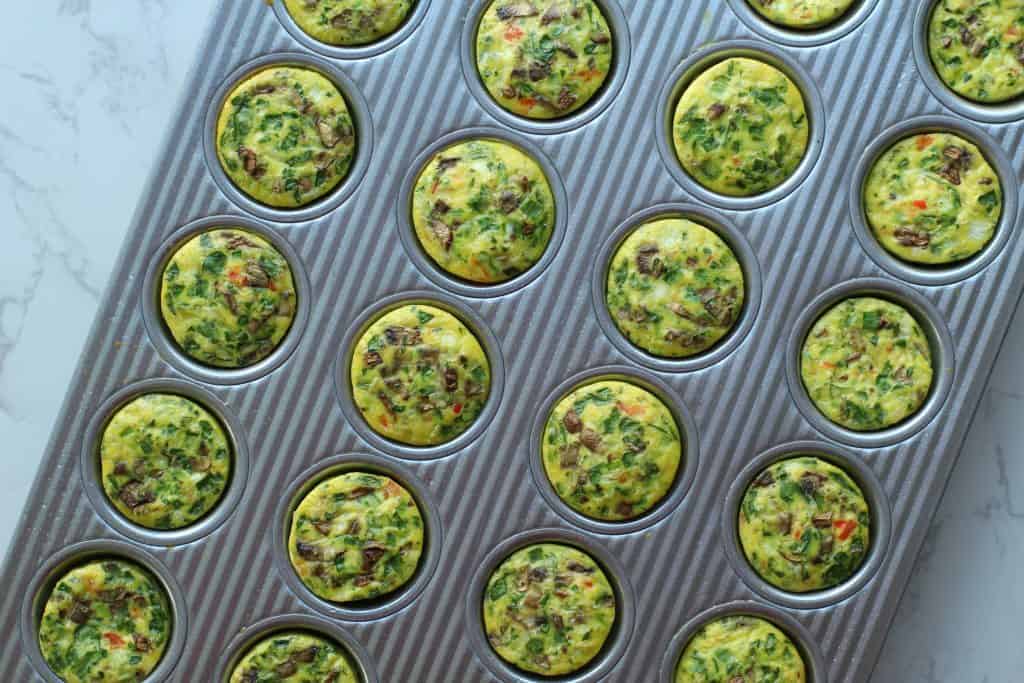 Cooked veggie egg bites in a silver mini muffin pan.