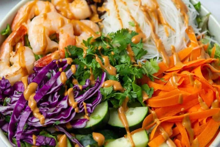 Summer dinner ideas: spring roll salad with cucumbers, carrots, cabbage, shrimp, and rice noodles drizzled with an orange sauce.
