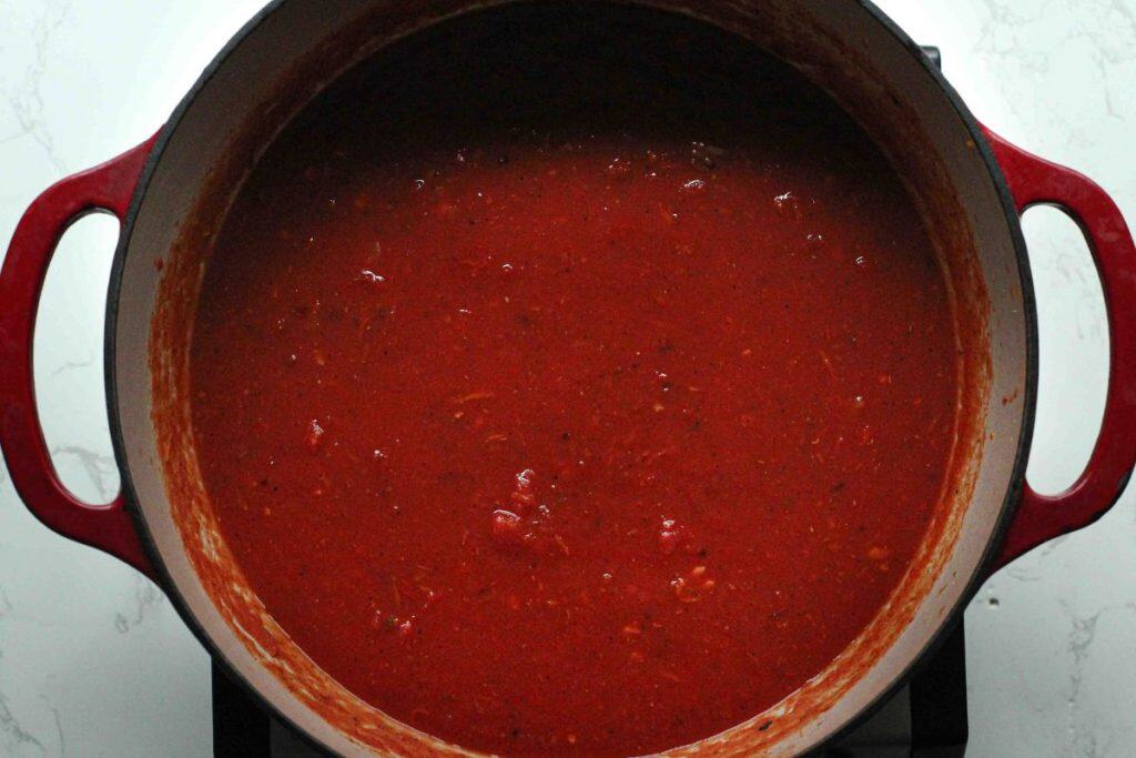 Marinara sauce in a dutch oven for beef stuffed shells.
