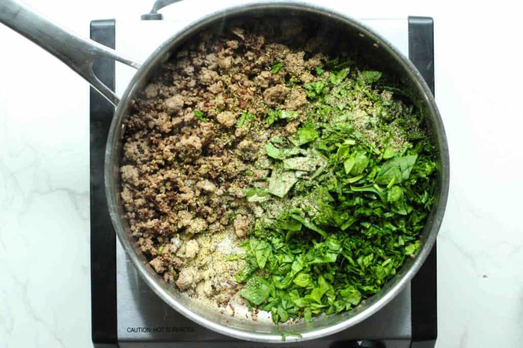 Beef stuffed shells ingredient in a pot: cooked ground beef, seasonings, and chopped spinach before cooking.
