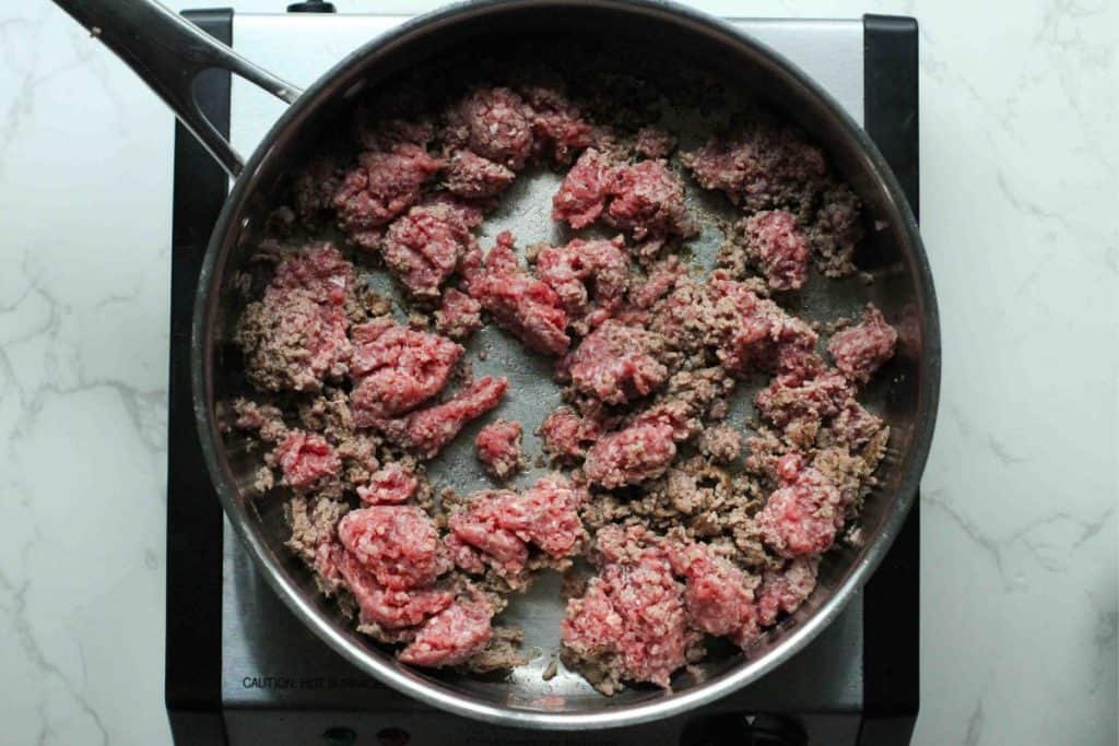 Ground beef being cooked in a stainless steel pan.